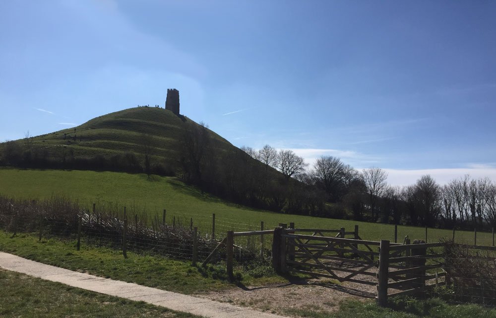 View of Glastonbury Tor, Green fields and hill with tower on top with blue sky