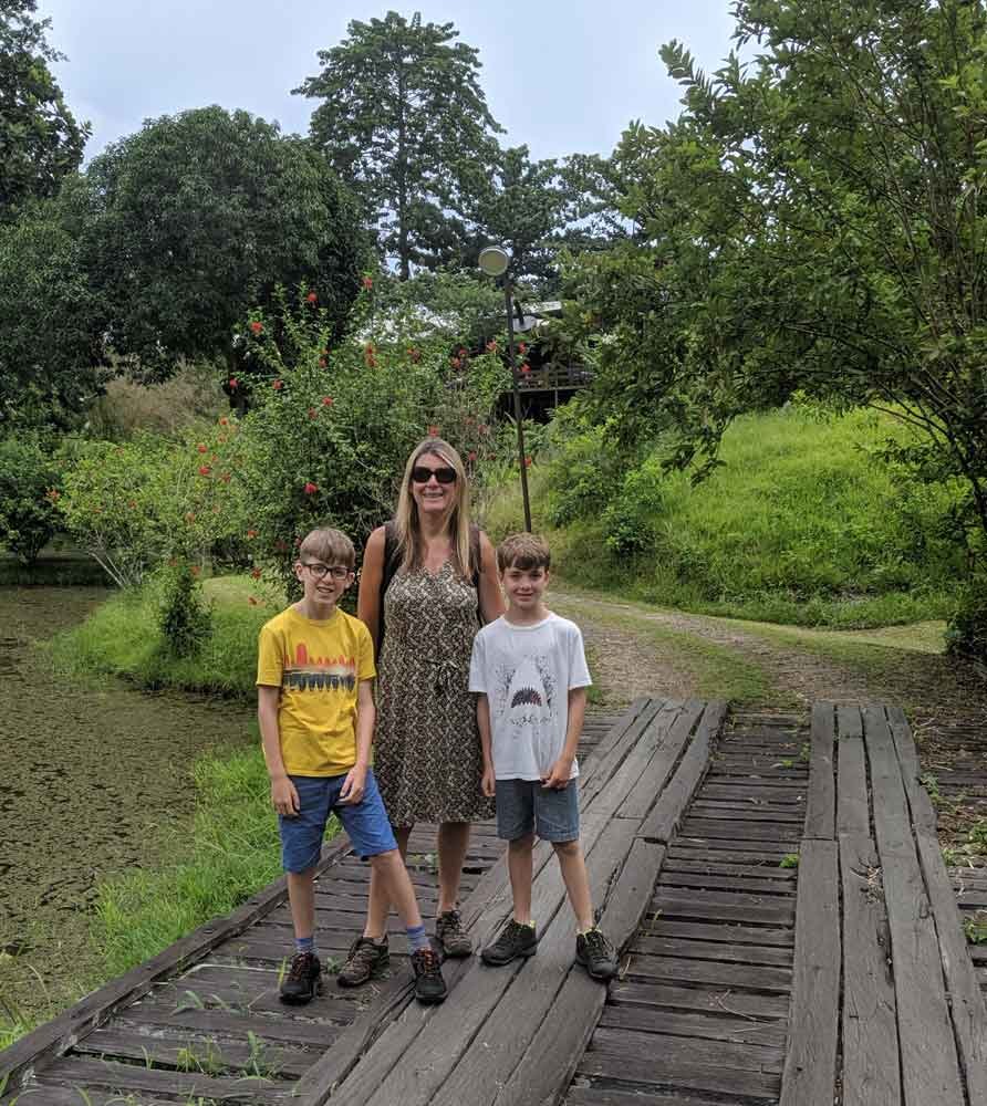 Forest Edge grounds mother and sons standing on wooden bridge in grounds of Forest Edge, Borneo